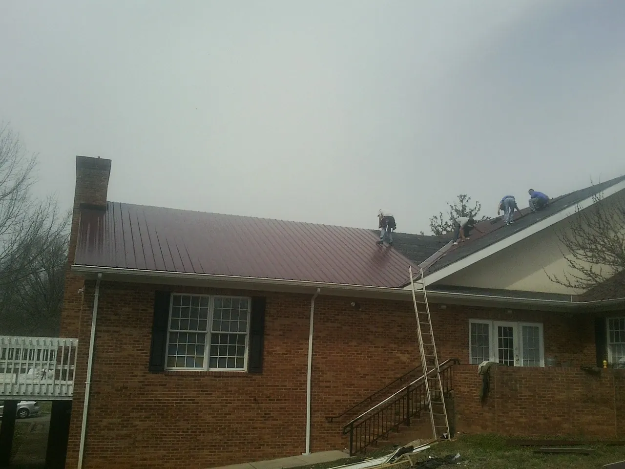 Crew setting red metal roofing panels on a brick home in Lilburn