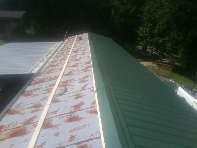Old rusted panels beside newly installed green metal roofing — Wind Damage Roof Repair by Roofing Brothers in Lilburn