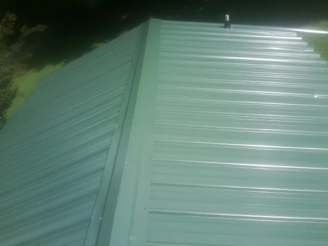 New green metal panels meeting at the ridge of a roof — Flat Roof Repair work by our crew in Lilburn