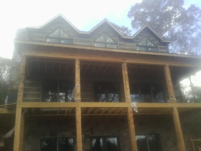 Dormers and porch framing on a large log home under construction — Roof Coating work by our crew in Lilburn