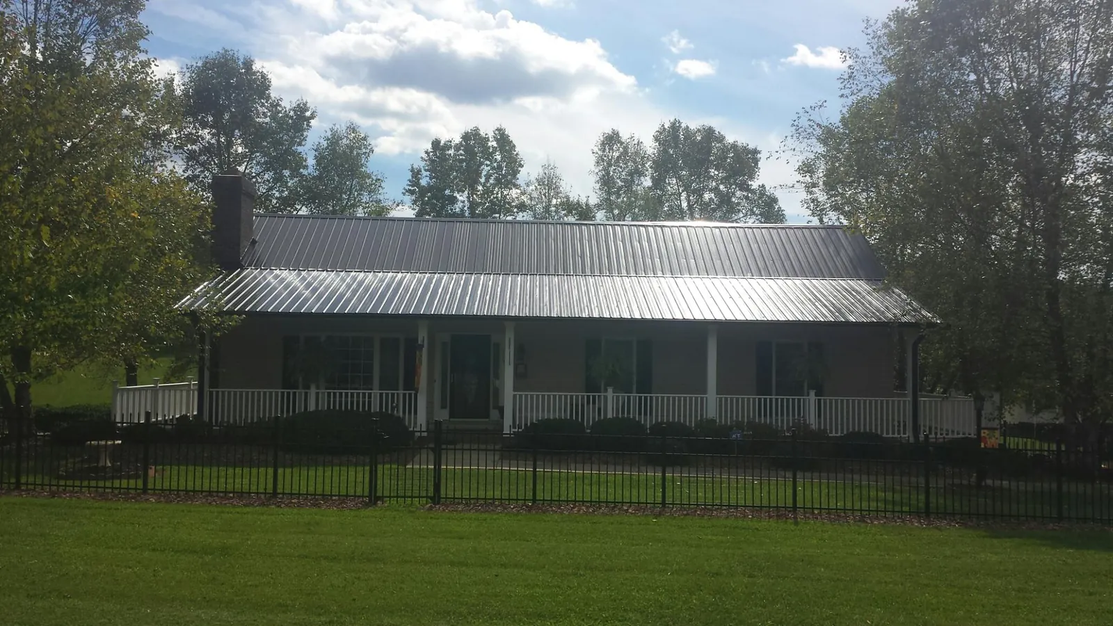 Gray metal roof on a brick ranch with a full width front porch — Gutter Guard Installation work by our crew in Lilburn