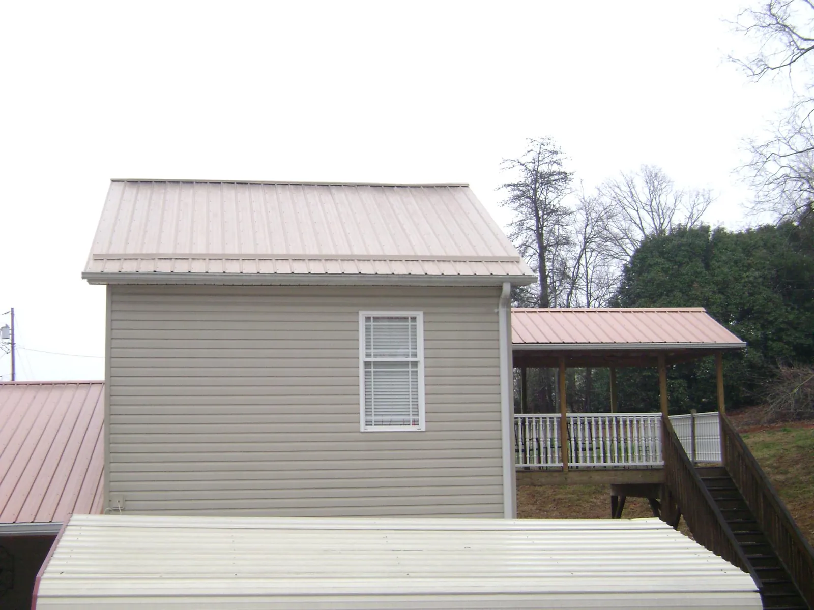 Tan metal roofs on a two story addition and attached porch, from a Roof Replacement job in Lilburn