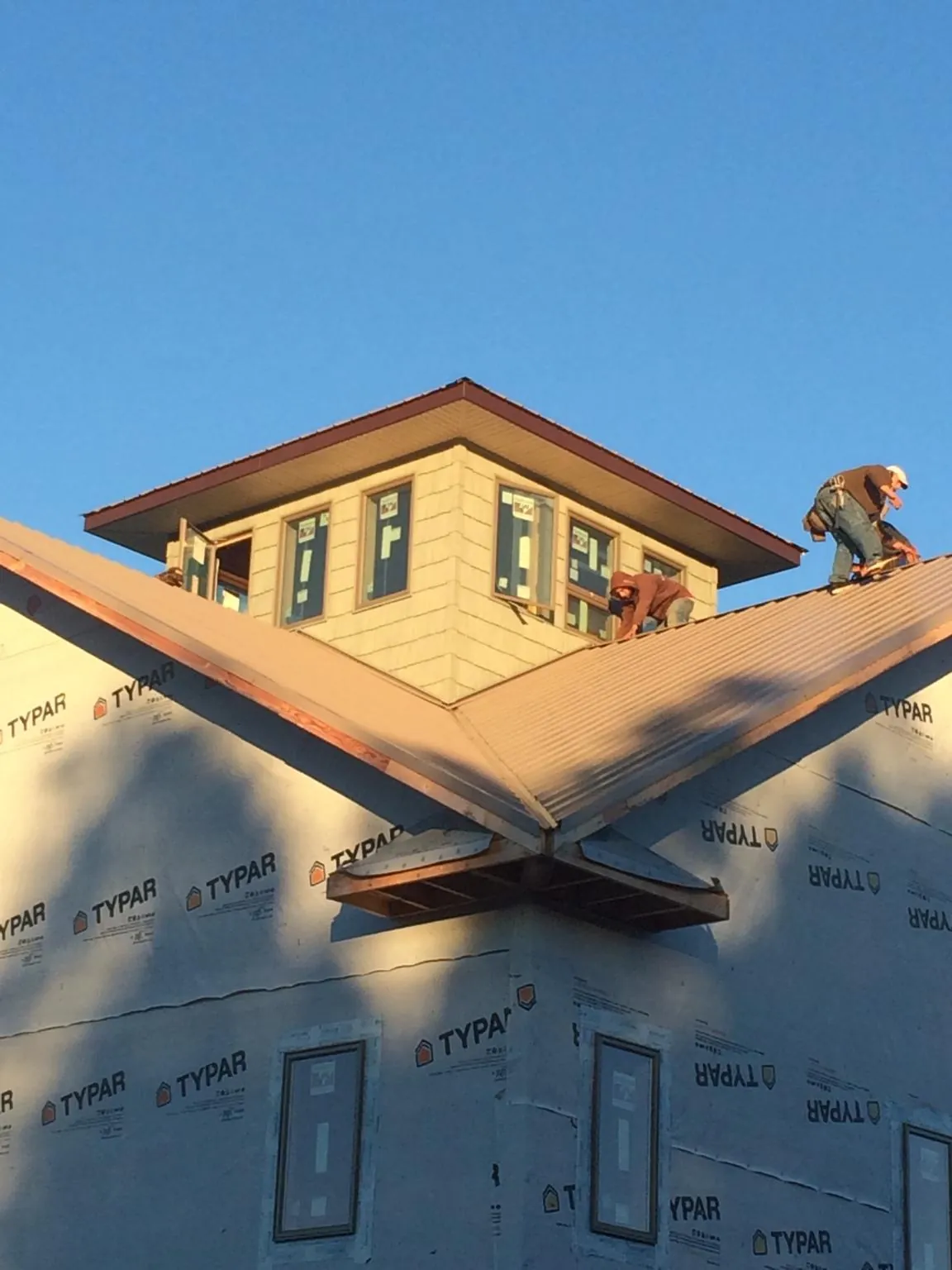 Roofers working around a rooftop cupola on a new metal roof at sunset — Roof Waterproofing in Lilburn by Roofing Brothers